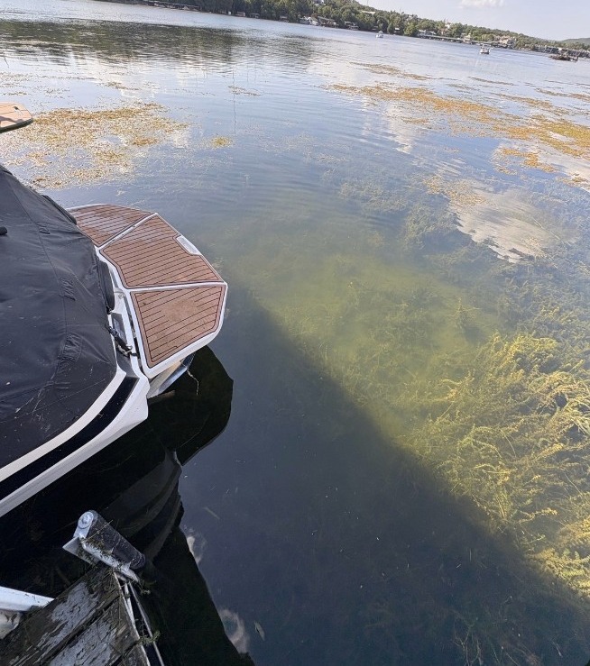 After: clear open water beside the same boat and dock on Lake Austin after hand-pulled hydrilla removal